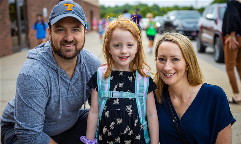 A mother, father and daughter smile